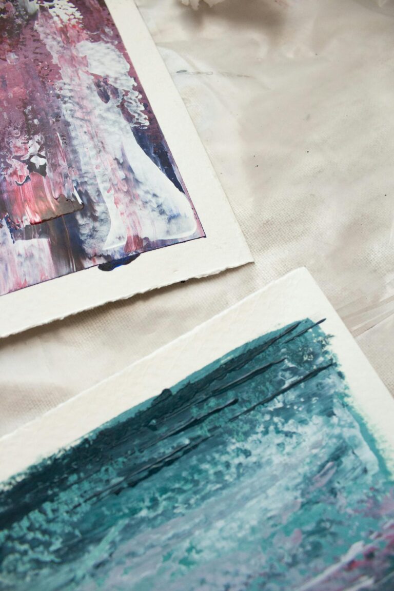 Close-up view of abstract paintings on textured paper, showcasing vibrant brushstrokes.